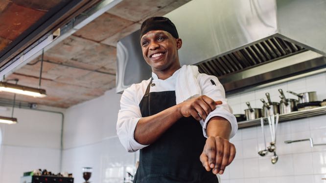 man in chef uniform in front of kitchen equipment
